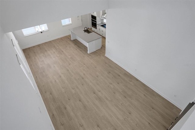 unfurnished living room featuring light wood-style flooring, baseboards, and a sink