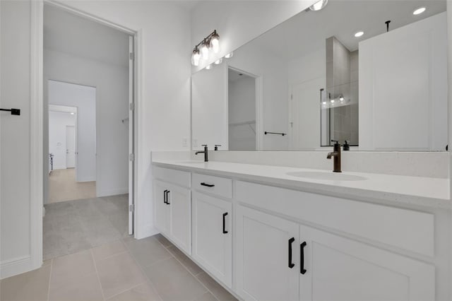 full bathroom with double vanity, tile patterned flooring, tiled shower, and a sink