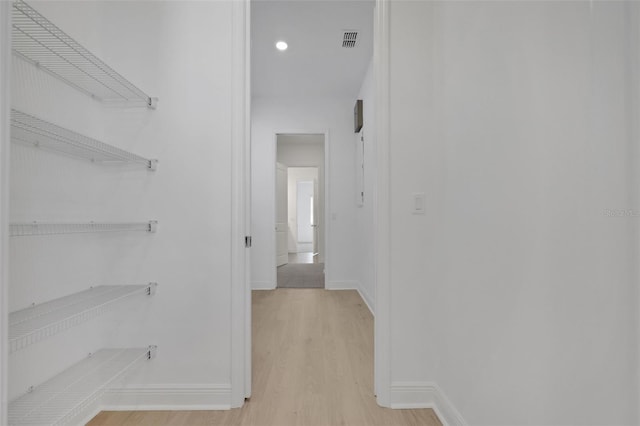 hallway with visible vents, light wood-type flooring, and baseboards