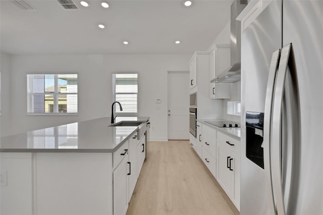 kitchen with visible vents, an island with sink, a sink, appliances with stainless steel finishes, and wall chimney exhaust hood