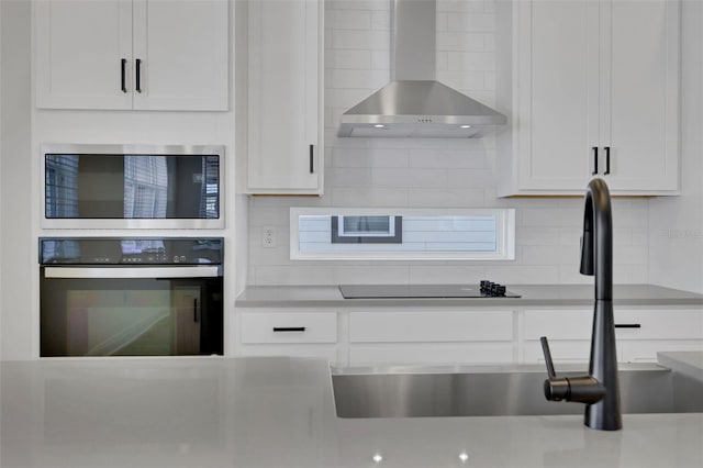 kitchen with a sink, oven, stainless steel microwave, wall chimney exhaust hood, and tasteful backsplash
