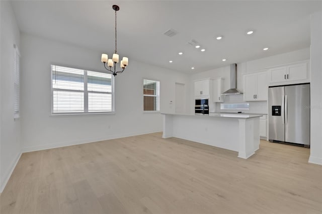 kitchen featuring stainless steel fridge with ice dispenser, light wood-style floors, white cabinetry, wall chimney range hood, and a chandelier