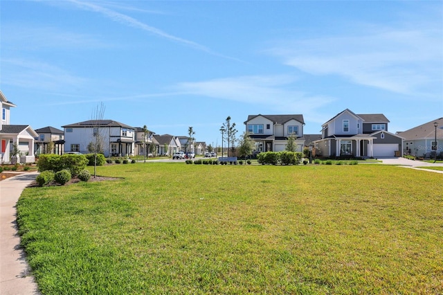 view of property's community featuring a garage, a residential view, a lawn, and concrete driveway