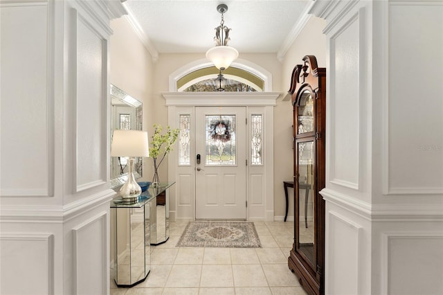foyer entrance with light tile patterned floors and ornamental molding
