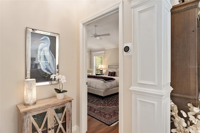 hall with wood finished floors and ornamental molding