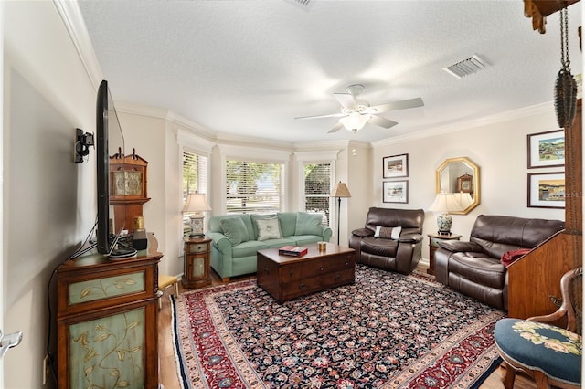 living room featuring visible vents, a textured ceiling, crown molding, and ceiling fan