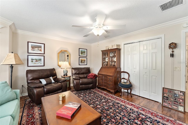 living room featuring crown molding, ceiling fan, visible vents, baseboards, and hardwood / wood-style flooring