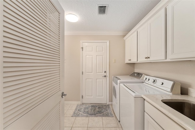 laundry area with a sink, crown molding, cabinet space, washer and clothes dryer, and light tile patterned flooring