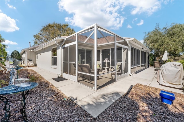 back of property with a sunroom, a patio, and stucco siding