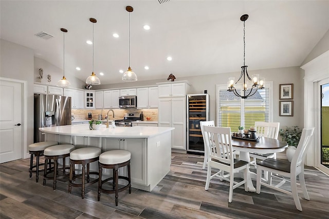 5557 Hawkins Dr, The Villages, FL 32163 - kitchen featuring backsplash, appliances with stainless steel finishes, vaulted ceiling, and beverage cooler