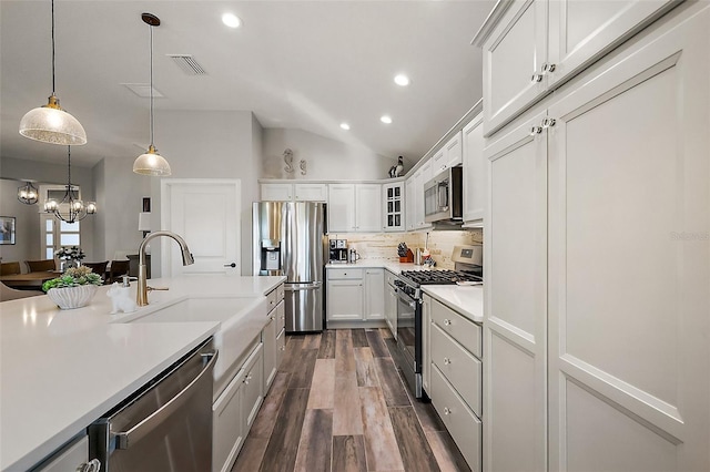5557 Hawkins Dr, The Villages, FL 32163 - kitchen featuring light countertops, tasteful backsplash, dark wood-type flooring, hanging light fixtures, and appliances with stainless steel finishes