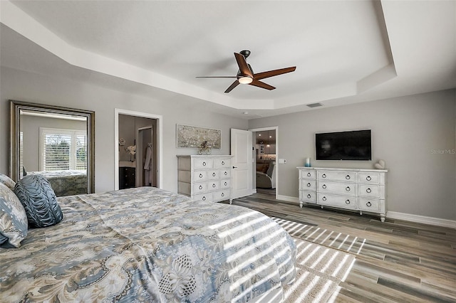 5557 Hawkins Dr, The Villages, FL 32163 - bedroom featuring baseboards, visible vents, a tray ceiling, and wood finished floors