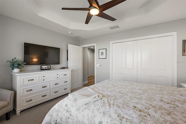 5557 Hawkins Dr, The Villages, FL 32163 - bedroom featuring a tray ceiling, dark colored carpet, visible vents, a ceiling fan, and a closet