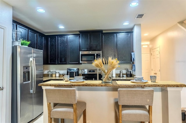 144 Primrose Dr, Davenport, FL 33837 - kitchen with a breakfast bar area, recessed lighting, dark cabinets, and appliances with stainless steel finishes