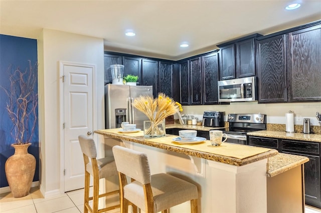 144 Primrose Dr, Davenport, FL 33837 - kitchen featuring a kitchen island, a kitchen bar, appliances with stainless steel finishes, light tile patterned floors, and recessed lighting
