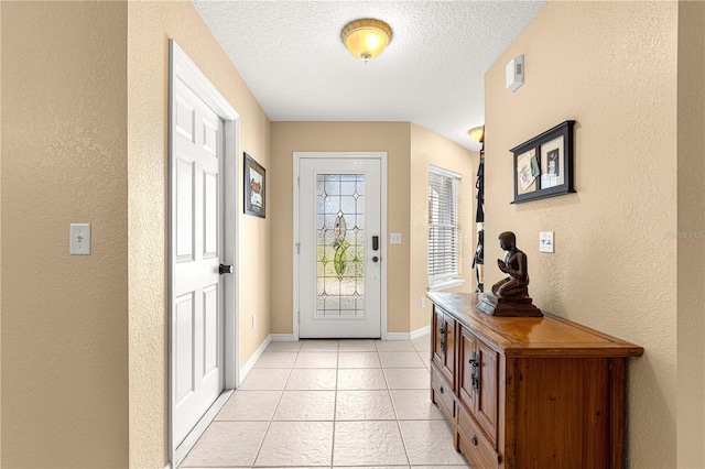 foyer featuring baseboards, a textured ceiling, a textured wall, and light tile patterned floors