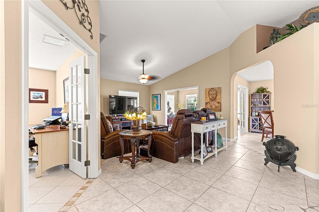 living area featuring light tile patterned flooring, arched walkways, lofted ceiling, and visible vents