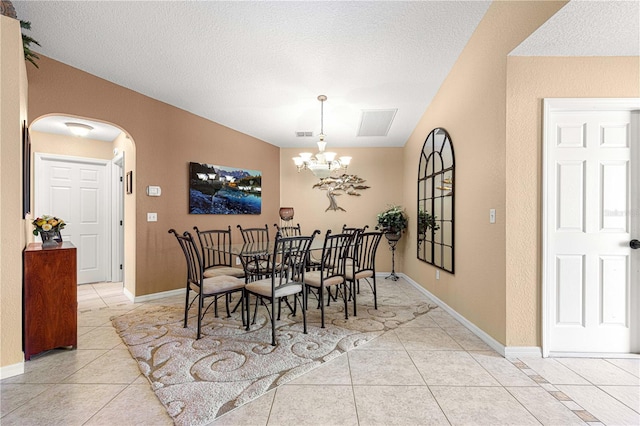 dining room featuring arched walkways, a textured ceiling, a notable chandelier, and light tile patterned flooring