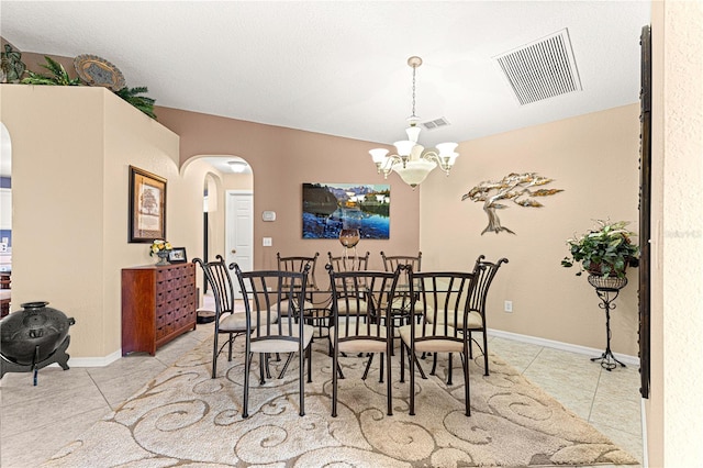 dining room with visible vents, a notable chandelier, arched walkways, and tile patterned flooring