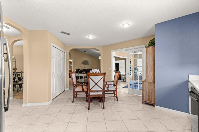 dining space featuring light tile patterned flooring, a textured ceiling, visible vents, arched walkways, and french doors