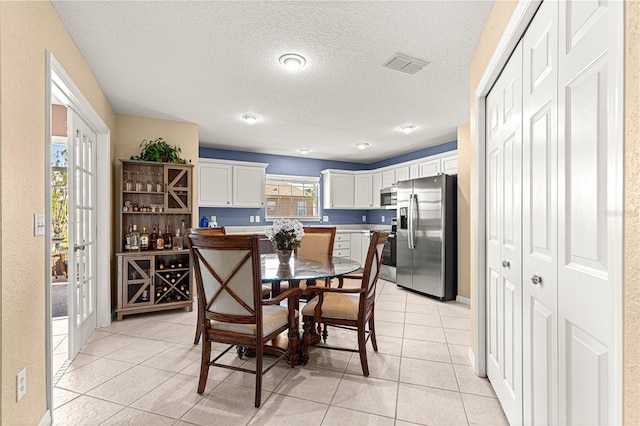 dining space featuring light tile patterned flooring, a textured ceiling, and visible vents