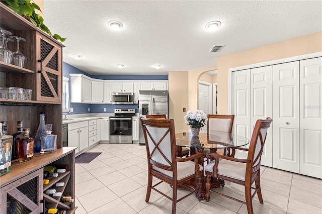 kitchen with visible vents, appliances with stainless steel finishes, arched walkways, a sink, and light tile patterned floors