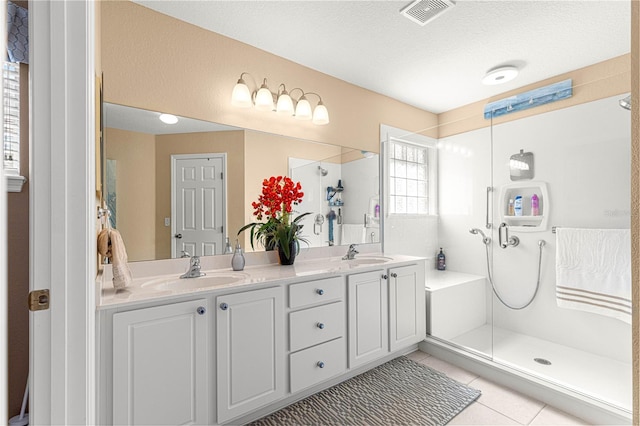 bathroom with tile patterned floors, a sink, a shower stall, and visible vents