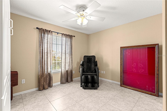 living area with tile patterned floors, a textured ceiling, baseboards, and ceiling fan