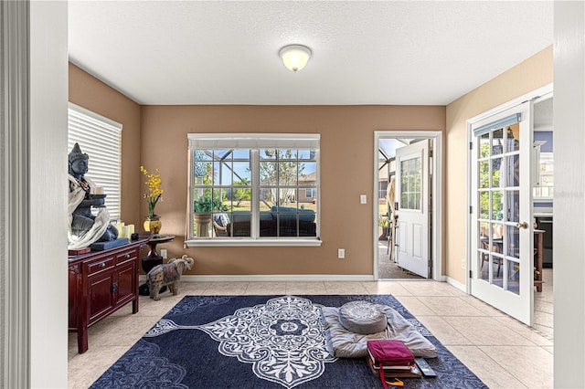 interior space with french doors, tile patterned flooring, baseboards, and a textured ceiling