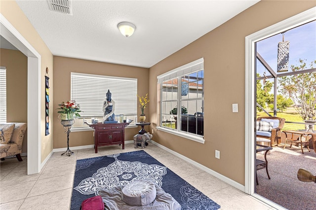 interior space with light tile patterned flooring, baseboards, a textured ceiling, and visible vents