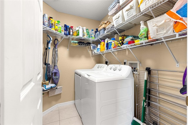 clothes washing area with washing machine and clothes dryer, tile patterned floors, baseboards, and laundry area