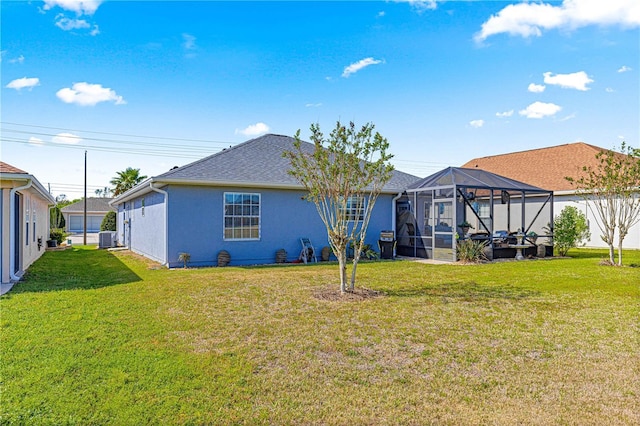 rear view of property featuring cooling unit, stucco siding, glass enclosure, a shingled roof, and a lawn