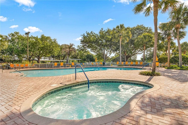 pool with a hot tub, fence, and a patio area