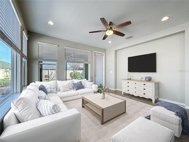 living area featuring baseboards, recessed lighting, ceiling fan, and a textured ceiling