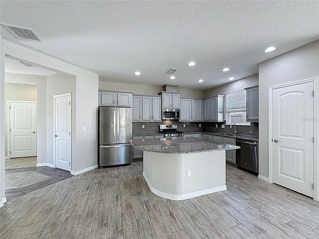 kitchen featuring gray cabinets, light wood-style flooring, stainless steel appliances, a sink, and visible vents