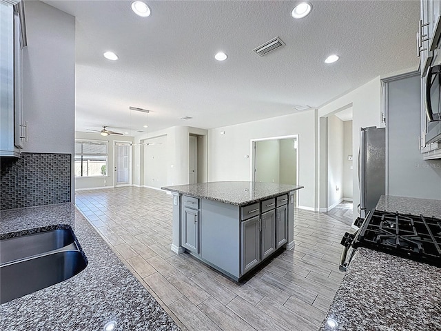 kitchen featuring visible vents, freestanding refrigerator, open floor plan, a ceiling fan, and gray cabinets