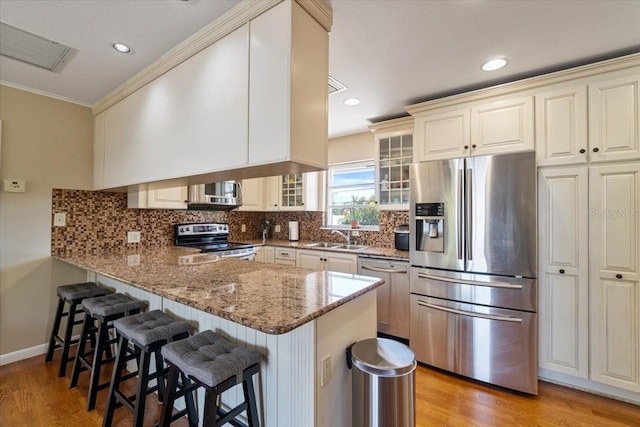 29051 Magnolia Ln, Big Pine Key, FL 33043 - kitchen featuring a peninsula, a breakfast bar, tasteful backsplash, appliances with stainless steel finishes, and glass insert cabinets