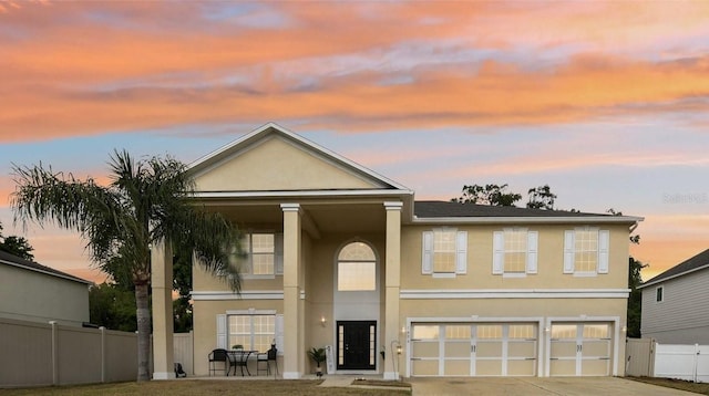view of front of house featuring fence, stucco siding, concrete driveway, and an attached garage