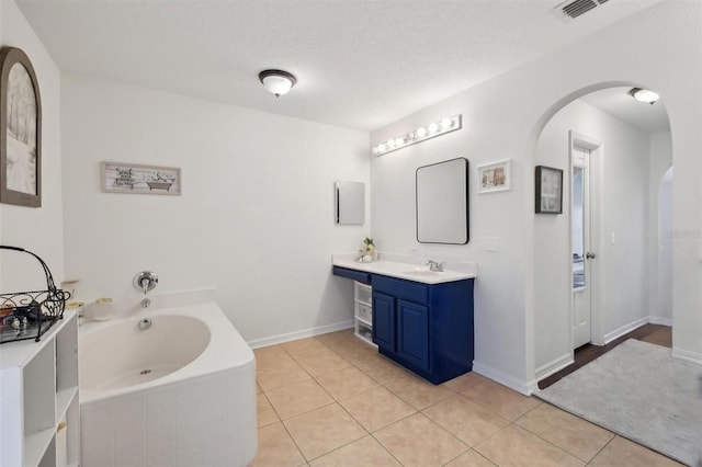 bathroom with tile patterned floors, vanity, baseboards, visible vents, and a garden tub
