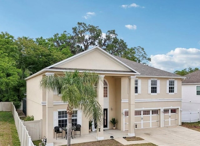 view of front of home with stucco siding, fence, driveway, and a garage