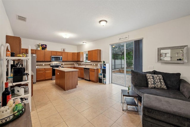 kitchen featuring stainless steel appliances, a kitchen island, light countertops, visible vents, and open floor plan