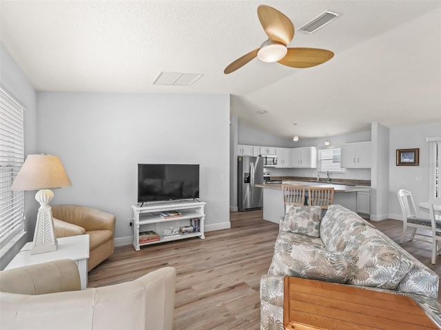 2111 Harston Trl, The Villages, FL 32162 - living area featuring visible vents, vaulted ceiling, a ceiling fan, and light wood finished floors