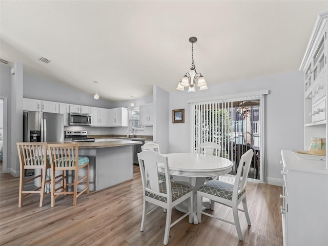 2111 Harston Trl, The Villages, FL 32162 - dining area featuring visible vents, light wood finished floors, baseboards, an inviting chandelier, and vaulted ceiling