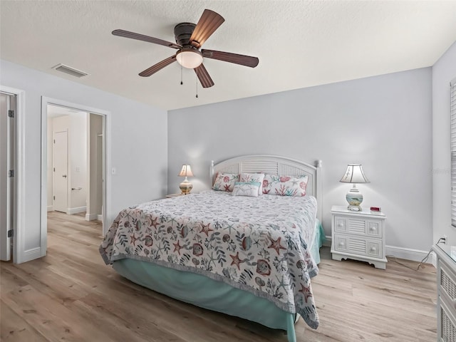 2111 Harston Trl, The Villages, FL 32162 - bedroom featuring light wood finished floors, a textured ceiling, baseboards, visible vents, and ceiling fan