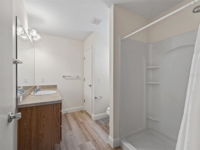 2111 Harston Trl, The Villages, FL 32162 - bathroom with toilet, vanity, a shower stall, wood finished floors, and visible vents