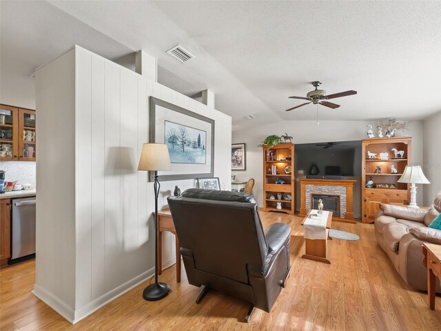 2376 Crk 444, Lake Panasoffkee, FL 33538 - living room featuring a ceiling fan, a fireplace, lofted ceiling, light wood-style flooring, and visible vents