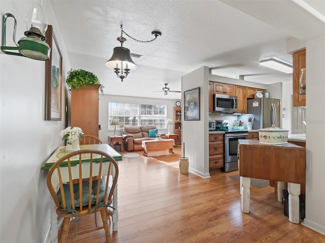 2376 Crk 444, Lake Panasoffkee, FL 33538 - kitchen featuring a textured ceiling, brown cabinets, light wood-type flooring, stainless steel appliances, and ceiling fan