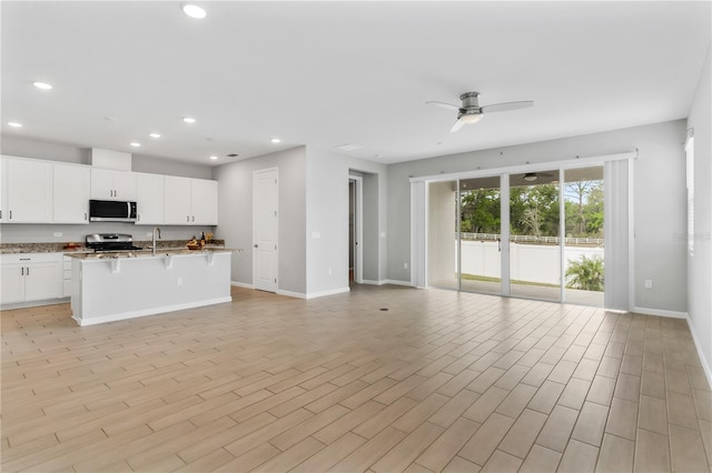 6003 Nightjar Ct, Okahumpka, FL 34762 - kitchen featuring a breakfast bar, ceiling fan, recessed lighting, appliances with stainless steel finishes, and open floor plan