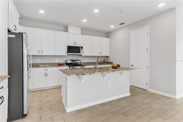 6003 Nightjar Ct, Okahumpka, FL 34762 - kitchen featuring visible vents, light stone countertops, a kitchen bar, appliances with stainless steel finishes, and a sink