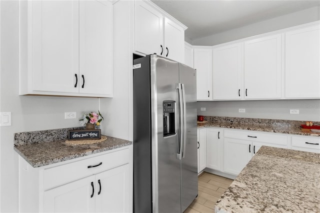 6003 Nightjar Ct, Okahumpka, FL 34762 - kitchen with stone countertops, white cabinetry, light wood-type flooring, and stainless steel refrigerator with ice dispenser